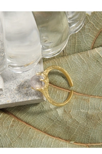 Macro shot of gold plated textured ring with claw-set round lavender zircon stone