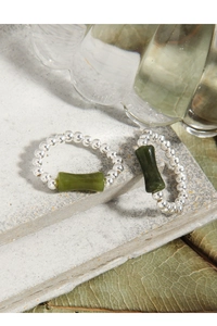 Detail of S925 sterling silver beaded ring with bamboo jade piece on stone surface