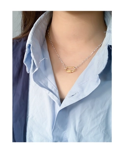Detail of silver S925 necklace featuring a gold U-shaped geometric pendant on a model