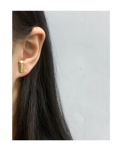 Close-up of minimalist rectangular gold earrings on model showing sleek metallic finish