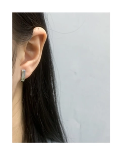 Close-up of minimalist silver rectangular huggie earring on model's ear with high-polish finish