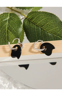 Macro shot of silver heart studs with black agate drops on a wooden display