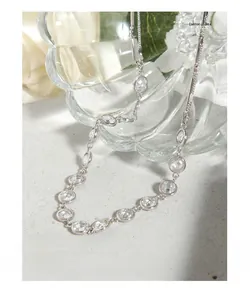 Détail du collier en argent S925 avec zircons ronds étincelants sur une surface grise