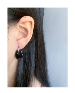 Close-up of minimalist black heart earrings in S925 silver on ear, modern chic style