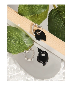 Macro shot of silver heart earrings with black onyx pendant on wooden texture