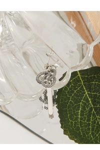 Detail view of a S925 sterling silver snake texture earring on a decorative glass display