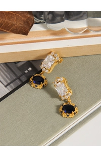 Close-up of vintage gold earrings featuring blue gemstones and micro-set zircon crystals