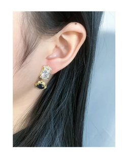 Close-up of vintage gold earrings with zircon and blue oval gemstone on model