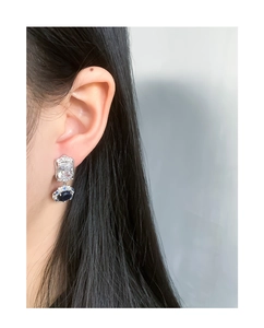 Close-up of S925 silver earrings with blue gemstones and zircons worn by a model