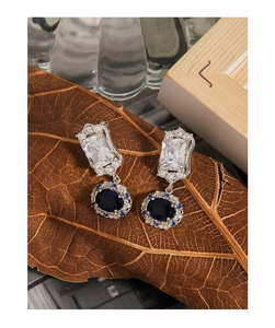 Macro shot of vintage silver earrings with rectangle and oval blue zirconia on a dry leaf