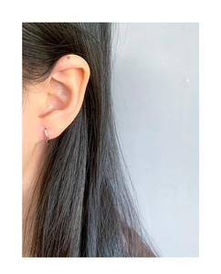 Gros plan d'une boucle d'oreille créole minimaliste en argent S925 sur le lobe