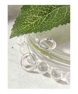 Macro détaillée des boucles d'oreilles minimalistes en argent S925 sur plateau en verre