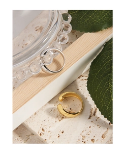 Polierte minimalistische offene Ringe in Gold und Silber auf strukturierter Oberfläche