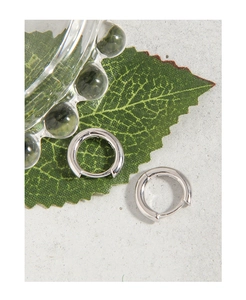 Gros plan de boucles d'oreilles créoles minimalistes en argent S925 sur fond gris texturé