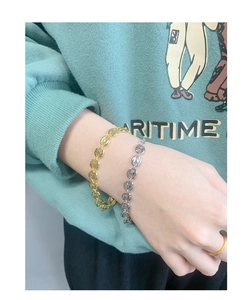 Close-up of stylish gold and silver pig nose link bracelets worn on a female wrist