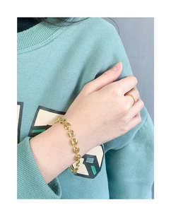 Detail of gold pig nose chain bracelet and simple band ring set on a model wrist