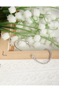 Detailed view of silver ear cuffs with sparkling cubic zirconia on a floral lace background