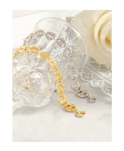 Close-up of gold and silver pig nose link bracelets wrapped around a glass on lace