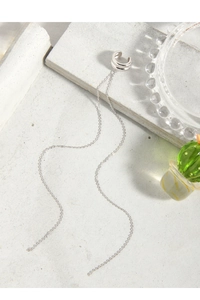 Detail of S925 silver ear cuff with elegant long tassel chains on a grey stone surface