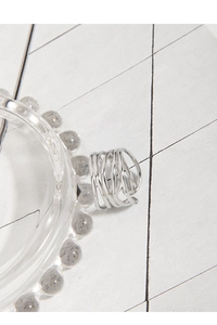 Macro shot of silver S925 multi-layer winding ring on a minimalist glass tray