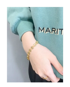 Detail of gold pig nose chain bracelet worn by a model with a minimalist gold ring