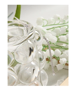 Macro shot of silver tassel earring with sparkling zircons hanging on glass rim