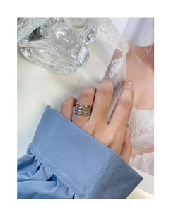 Macro view of multi-layer silver winding ring on finger with high-polish metallic texture