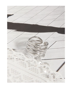 Close-up of a minimalist silver geometric multi-layer intertwined ring on lace fabric