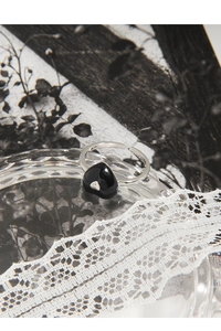Macro shot of S925 sterling silver ring with a black heart motif on a rippled glass bowl