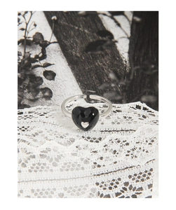 Macro shot of silver S925 heart ring with black enamel on elegant white lace fabric