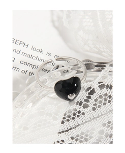 Close-up of minimalist S925 silver heart ring with black enamel inlay and lace detail