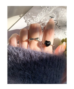 Detail of silver textured ring and black heart ring set worn on model's fingers