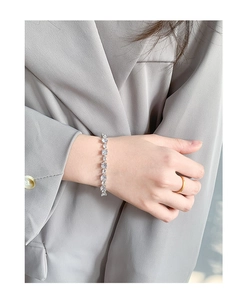 Detail of S925 sterling silver bracelet with sparkling cubic zirconia on a grey suit sleeve