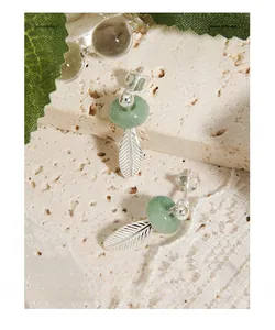 Close-up of S925 silver stud earrings with green jade beads and feather leaf charms