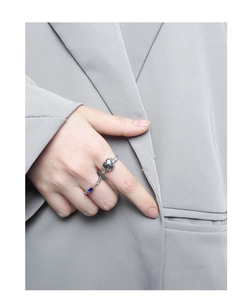 Détail de bagues en argent S925 avec texture cœur et pierre bleue sur main de mannequin
