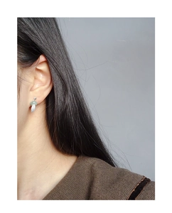 Detail of S925 silver feather earring with light green jade bead on model ear