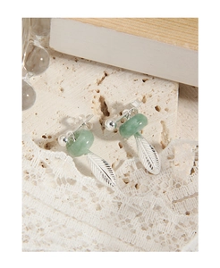 Macro shot of silver jade leaf earrings on a natural stone with lace background