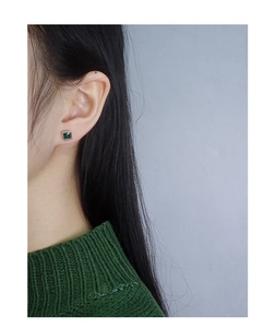 Close-up of square emerald zircon stud earrings worn on earlobe for a luxury look