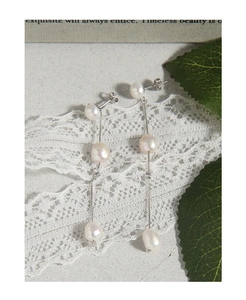 Détail de boucles d'oreilles pendantes en argent avec trois perles blanches naturelles