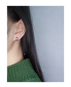 Close-up of minimalist silver double-hoop earrings worn by a model in a green sweater