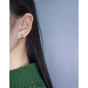 Minimalist double layer silver hoops on model wearing dark green knitted sweater