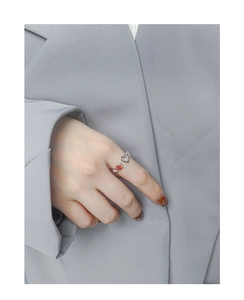 Detail of silver S925 open ring featuring an orange zircon gem and hollow heart design
