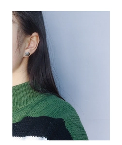 Macro view of minimalist S925 sterling silver shell earrings worn on earlobe