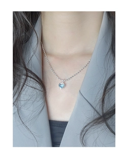 Détail du collier coeur en argent S925 avec zircon bleu porté par un mannequin en costume