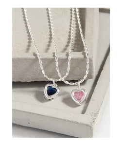 Détail macro de pendentifs cœur en cristal bleu et rose sur des chaînes à billes argentées