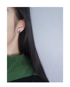 Close-up of minimalist S925 silver shell stud earring worn by a model in soft lighting