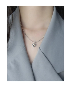 Détail d'un collier cœur en argent avec pierre zircon porté sur un col de veste gris
