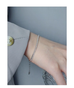 Close-up of S925 sterling silver geometric chain bracelet worn with casual blazer