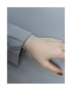 Sparkling S925 sterling silver geometric bracelet on female wrist with grey suit sleeve