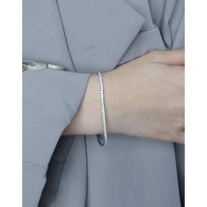 Sparkling S925 sterling silver tennis bracelet with shimmering zircons on a grey suit cuff